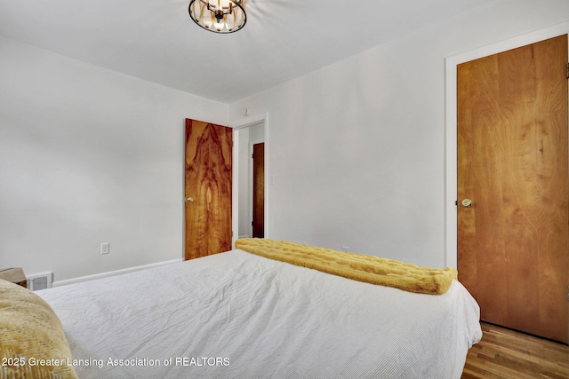 bedroom with an inviting chandelier and hardwood / wood-style floors