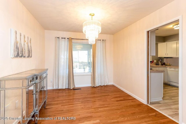 unfurnished dining area featuring a chandelier and light hardwood / wood-style flooring