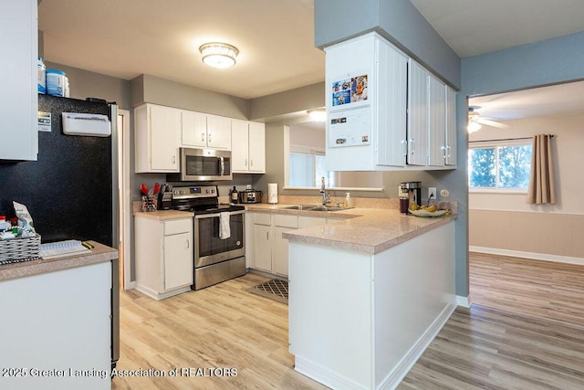 kitchen with sink, ceiling fan, appliances with stainless steel finishes, white cabinetry, and light wood-type flooring