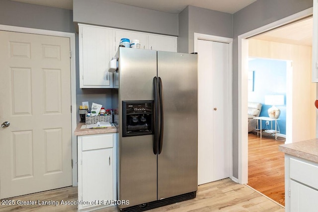 kitchen with light hardwood / wood-style flooring, white cabinets, and stainless steel refrigerator with ice dispenser