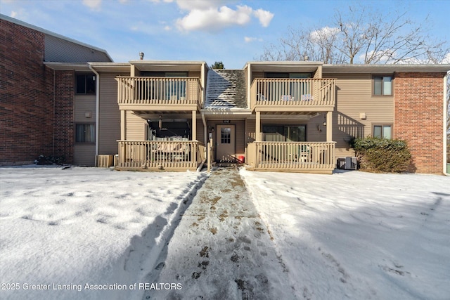 snow covered rear of property with cooling unit and a balcony