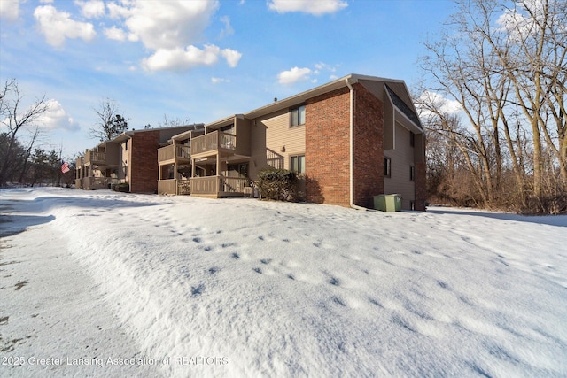 snow covered rear of property featuring a balcony