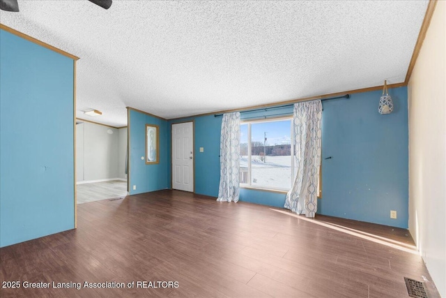 empty room featuring dark wood-type flooring, crown molding, and a textured ceiling