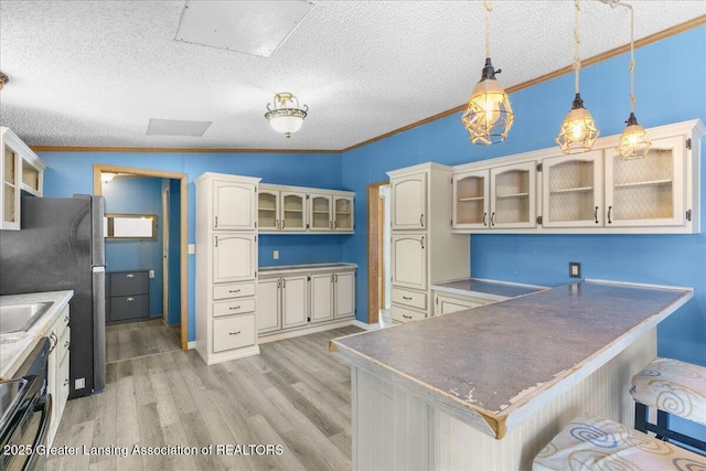 kitchen with ornamental molding, a breakfast bar, pendant lighting, and light hardwood / wood-style floors