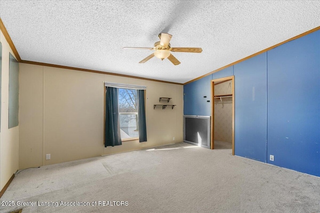 unfurnished bedroom featuring ceiling fan, ornamental molding, a textured ceiling, and carpet flooring