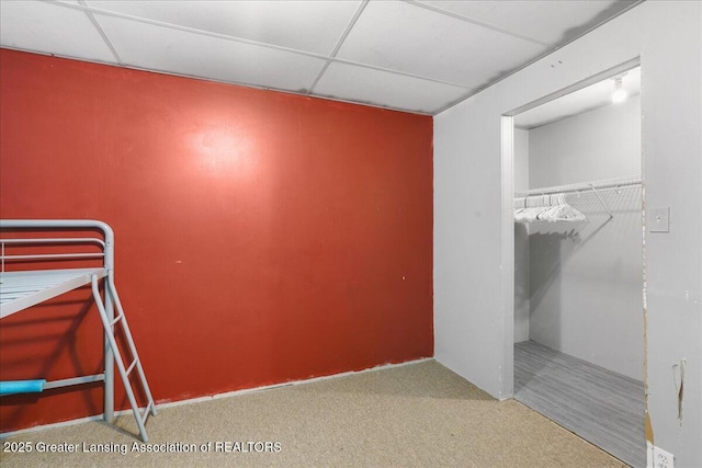 unfurnished bedroom featuring carpet floors, a paneled ceiling, and a closet