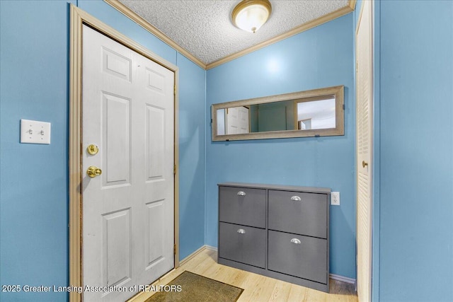 entryway with ornamental molding, a textured ceiling, and light hardwood / wood-style floors