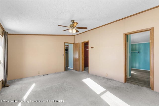 unfurnished bedroom featuring crown molding, a spacious closet, light carpet, and a textured ceiling