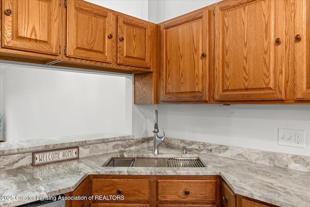 kitchen with light stone counters, dishwasher, and sink