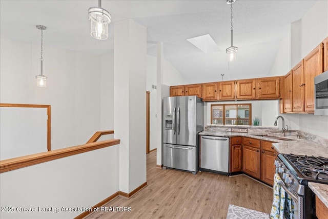 kitchen featuring sink, a skylight, hanging light fixtures, light hardwood / wood-style flooring, and stainless steel appliances