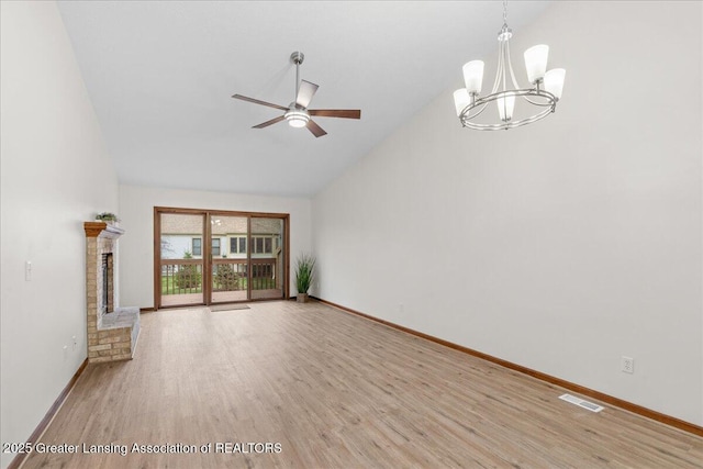 unfurnished living room with ceiling fan with notable chandelier, high vaulted ceiling, and light hardwood / wood-style flooring