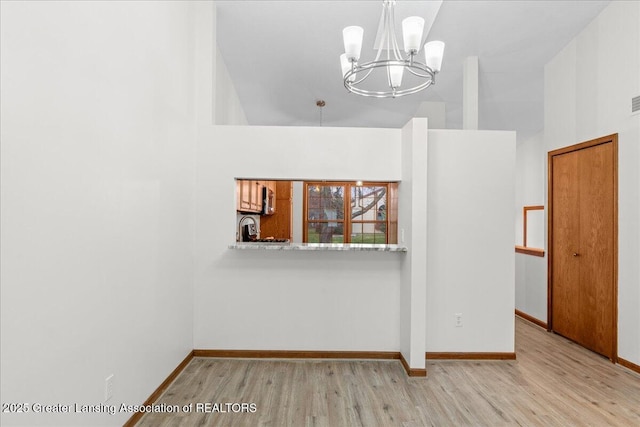 interior space featuring a towering ceiling, a chandelier, and light hardwood / wood-style flooring