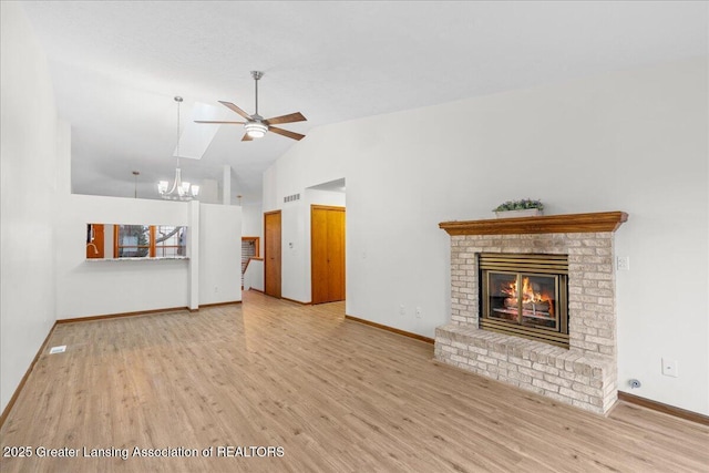 unfurnished living room featuring a brick fireplace, ceiling fan with notable chandelier, light hardwood / wood-style flooring, and high vaulted ceiling