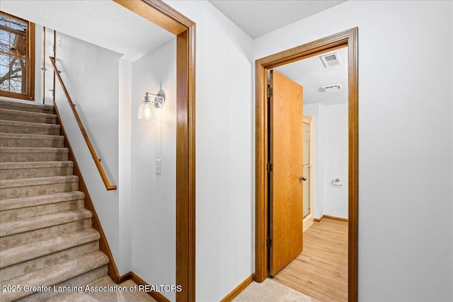 staircase with hardwood / wood-style floors and a textured ceiling