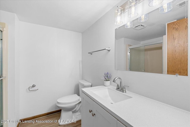 bathroom featuring vanity, hardwood / wood-style flooring, a shower with shower door, and toilet