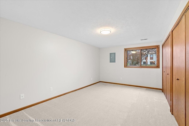 unfurnished bedroom with light carpet, electric panel, a closet, and a textured ceiling