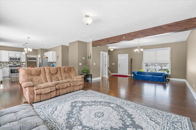 living room with beamed ceiling, a chandelier, dark wood-type flooring, and a textured ceiling