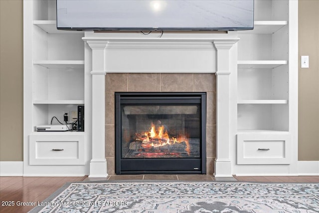 room details with built in shelves, a fireplace, and hardwood / wood-style flooring