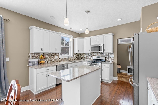 kitchen featuring white cabinetry, decorative light fixtures, a center island, and appliances with stainless steel finishes