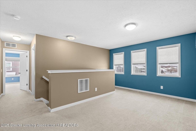 empty room with light colored carpet and a textured ceiling