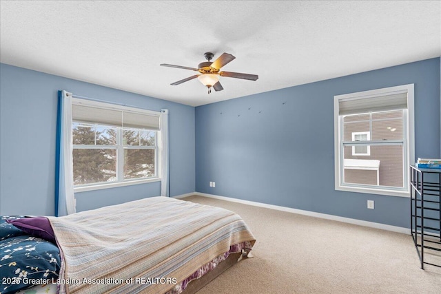 bedroom with ceiling fan, light colored carpet, and a textured ceiling