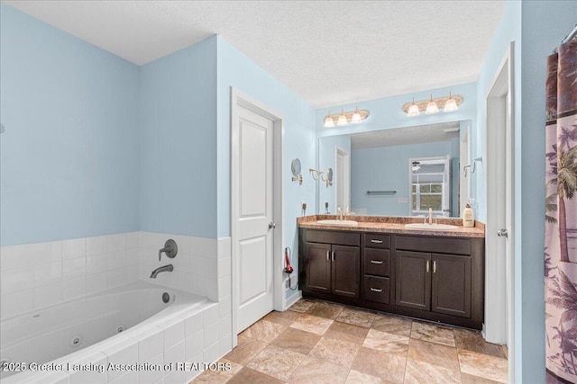 bathroom with vanity, tiled bath, and a textured ceiling