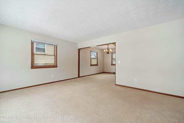 carpeted spare room featuring a notable chandelier and a textured ceiling