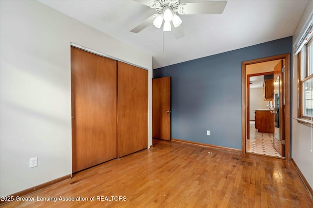 unfurnished bedroom with ceiling fan, connected bathroom, a closet, and light wood-type flooring