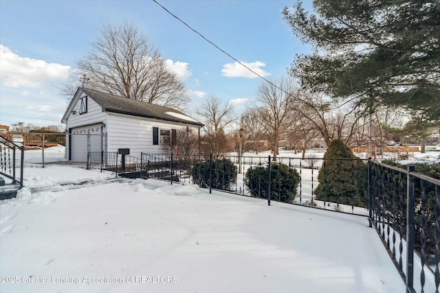 snowy yard with a garage and an outbuilding