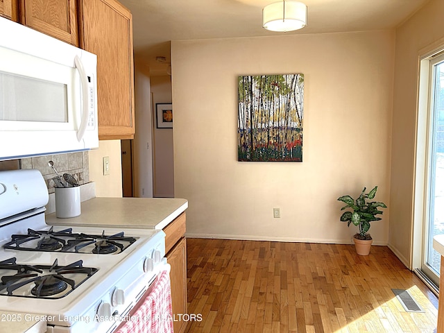 kitchen featuring tasteful backsplash, white appliances, and light wood-type flooring