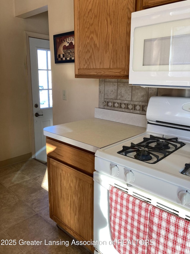 kitchen featuring dark tile patterned floors, backsplash, and white appliances