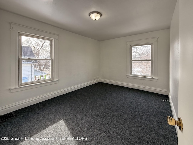 empty room featuring dark colored carpet and plenty of natural light