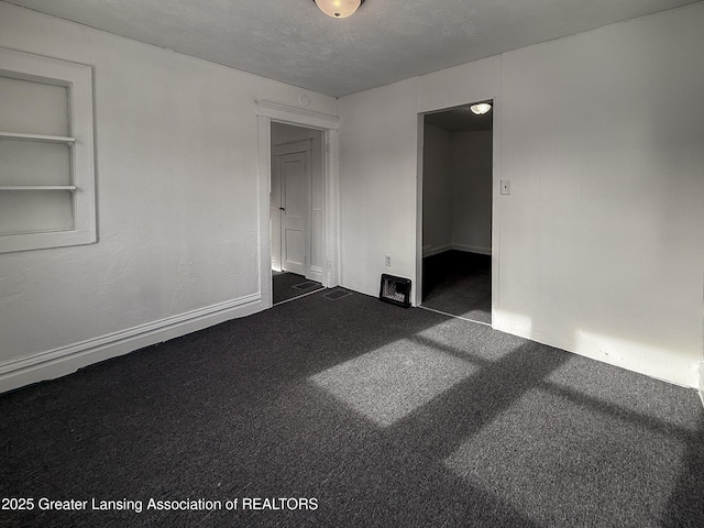 carpeted spare room featuring a textured ceiling and built in shelves