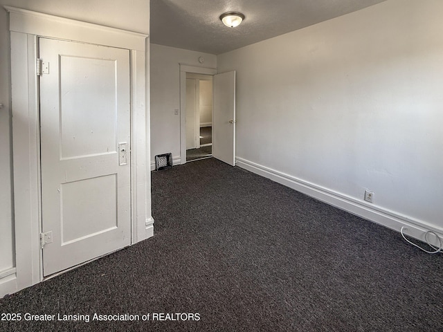 unfurnished bedroom featuring dark carpet and a textured ceiling