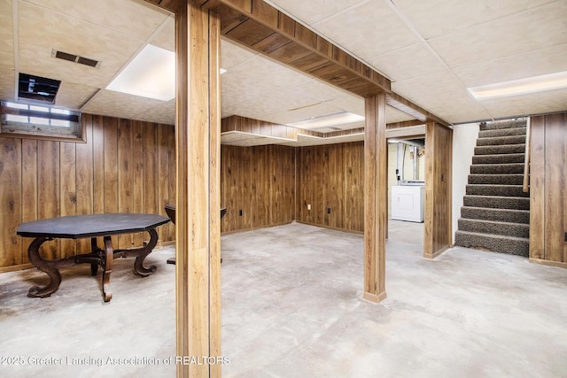 basement featuring washer / clothes dryer, a paneled ceiling, and wood walls