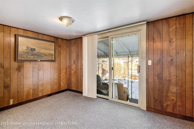 empty room featuring light colored carpet and wood walls