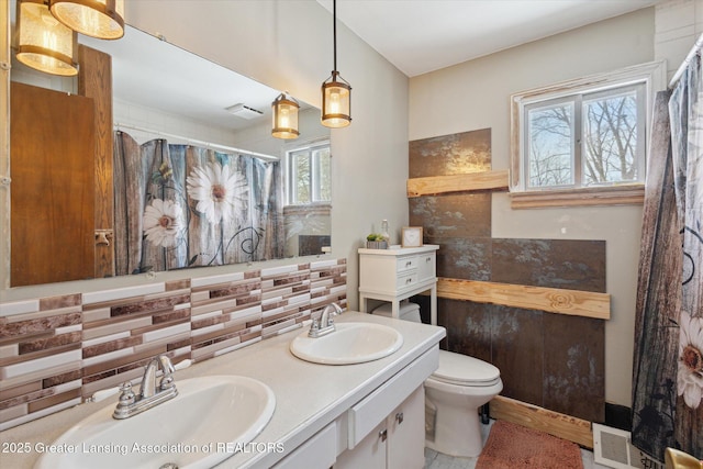 bathroom featuring vanity, toilet, and decorative backsplash