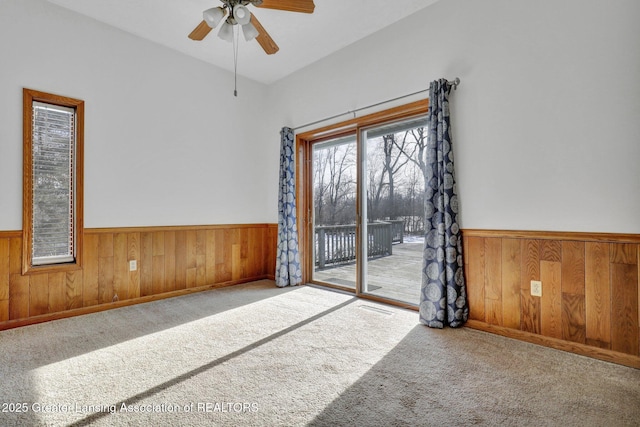 carpeted spare room featuring ceiling fan and wood walls