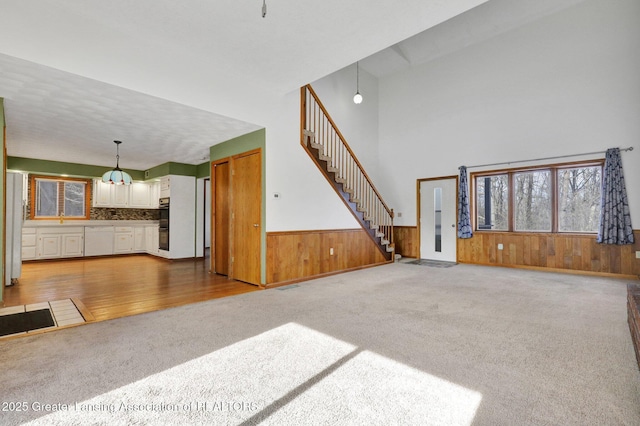 unfurnished living room featuring carpet and wood walls