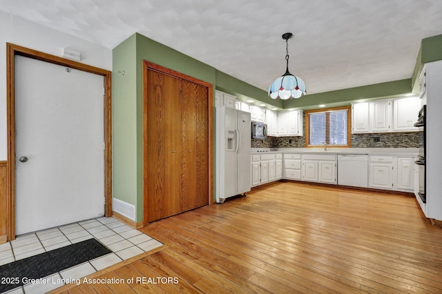 kitchen featuring decorative light fixtures, light hardwood / wood-style flooring, white cabinets, white appliances, and backsplash