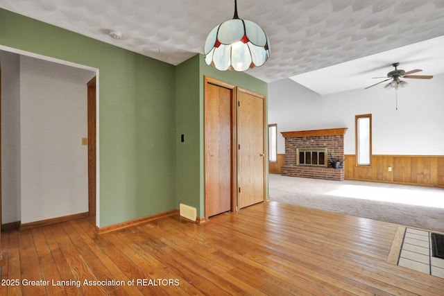 unfurnished living room with ceiling fan, a fireplace, and light hardwood / wood-style flooring