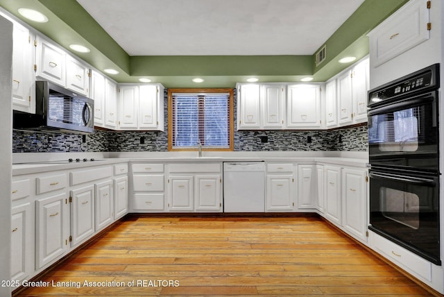 kitchen featuring white cabinetry, sink, backsplash, black appliances, and light hardwood / wood-style flooring