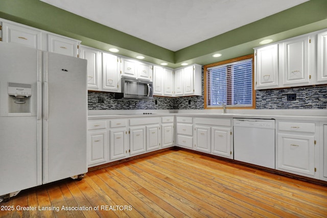 kitchen with tasteful backsplash, white cabinetry, white appliances, and light hardwood / wood-style flooring