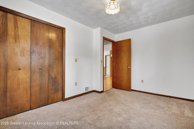 unfurnished bedroom featuring light colored carpet and a closet