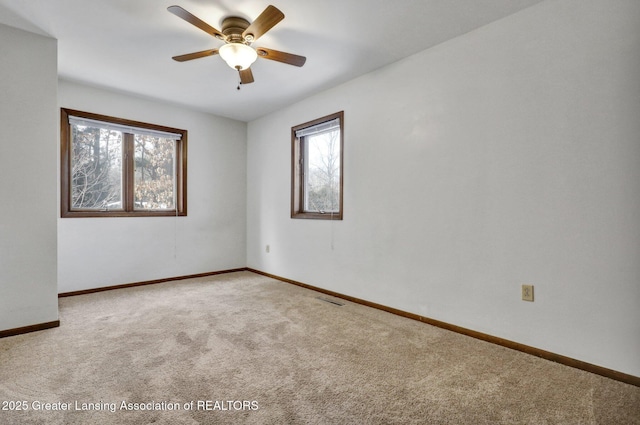 carpeted empty room with a wealth of natural light and ceiling fan