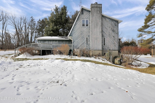 snow covered back of property featuring a wooden deck