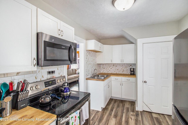 kitchen with sink, white cabinetry, wooden counters, appliances with stainless steel finishes, and dark hardwood / wood-style flooring