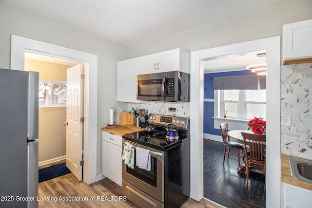 kitchen featuring stainless steel appliances, white cabinetry, wooden counters, and dark hardwood / wood-style flooring