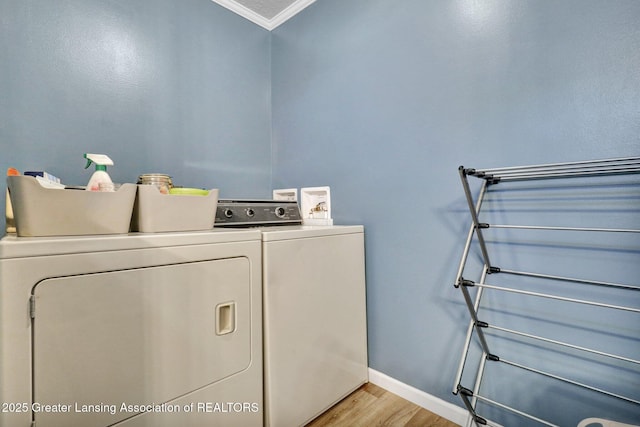 washroom with crown molding, washer and dryer, and light wood-type flooring