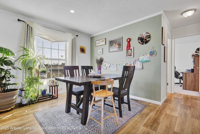 dining space with ornamental molding, a textured ceiling, and light hardwood / wood-style floors